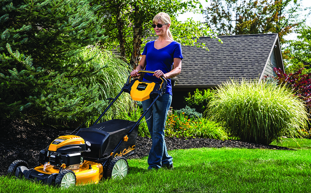 woman pushing lawn mower through grass